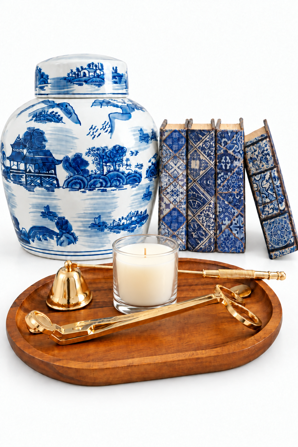 Blue and white chinoiserie ginger jar set with book boxes, glass candle, wood tray and gold-tone tools on a white background